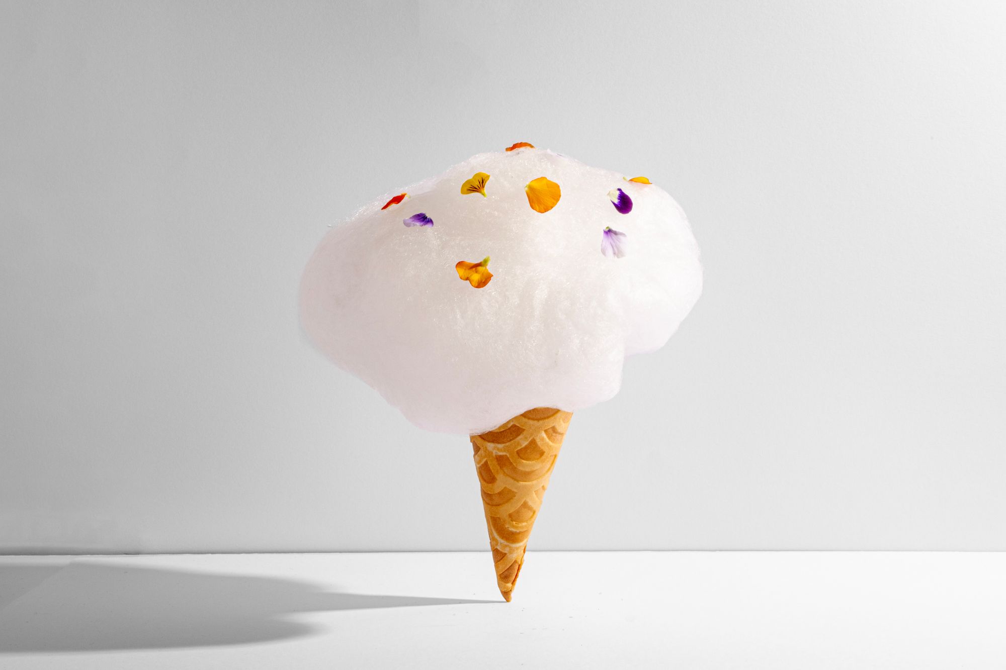 An ice cream cone overflowing with a pile of cotton candy.